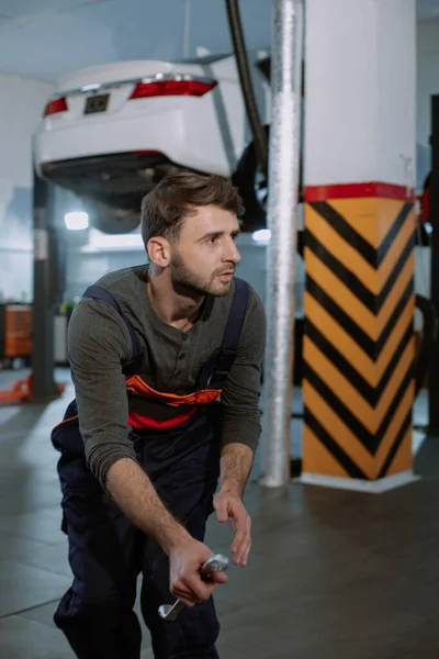 Een jonge monteur zit op een skateboard, die zijn handen laat zien aan de camera. — Stockfoto