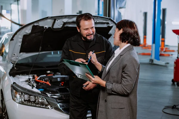 Service auto center monteur hebben een gesprek met de klant vrouw ze toont ondertekende documenten — Stockfoto
