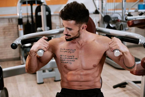 Spor salonunda barbell tezgah basın egzersiz yapıyor Gömleksiz kaslı genç adam