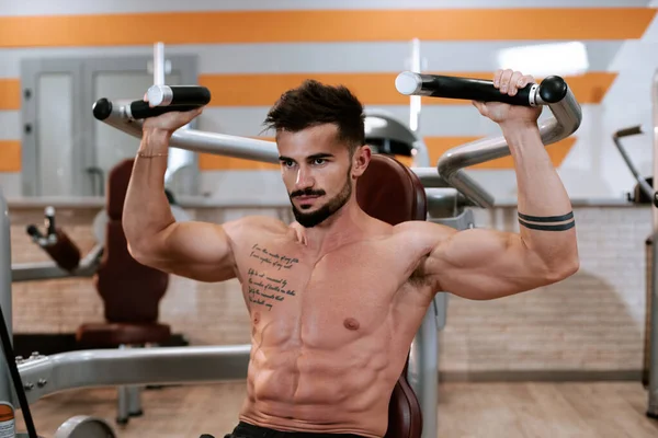 Spor salonunda barbell tezgah basın egzersiz yapıyor Gömleksiz kaslı genç adam