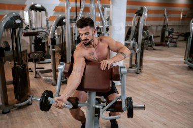 Ayrıntılar vücut geliştirme adam büyük bir geniş spor salonu portre pişmiş pazı egzersiz dumbbell kadar kaldırma egzersizleri yapıyor