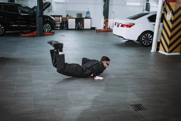Homem mecânico atraente em um centro de serviço moderno dançando engraçado na frente da câmera ele faz uma pausa do trabalho — Fotografia de Stock