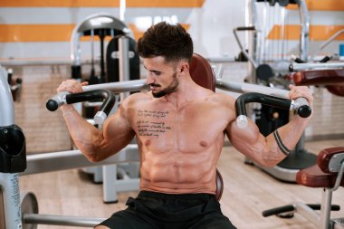 Spor salonunda spor yapmaya odaklanan kaslı sporcu vücut geliştirici spor modeli.