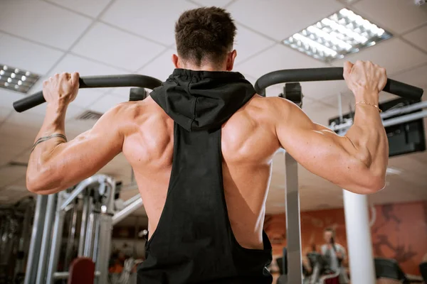 В современном тренажерном зале мускулистый человек делает упражнения для своих трицепсов сосредоточенно работает — стоковое фото