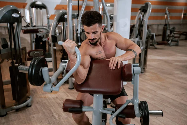 Detalhes musculação homem fazendo exercícios em um grande e espaçoso ginásio retrato biceps cozido treino levantando o haltere — Fotografia de Stock