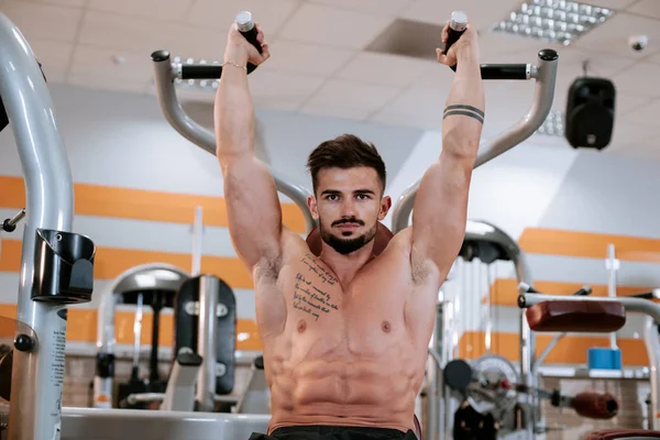 Erős sportos fiatalember testépítő fitnesz modell gyakorlat tricepsz súlyzó a padon, edzőteremben — Stock Fotó