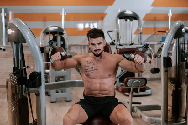 Мускулистый атлетичный молодой человек бодибилдер фитнес-модель, фокусирующаяся на упражнениях с в тренажерном зале — стоковое фото