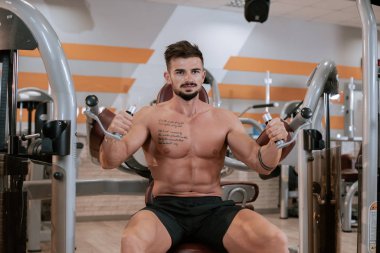 Spor salonunda barbell tezgah basın egzersiz yapıyor Gömleksiz kaslı genç adam