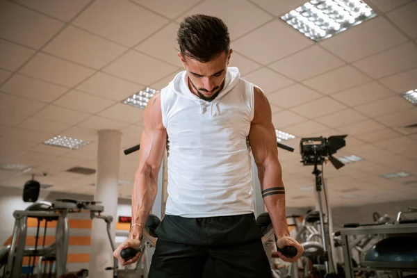 Em um moderno ginásio homem musculoso fazendo exercícios para seu tríceps concentrado trabalhando duro — Fotografia de Stock