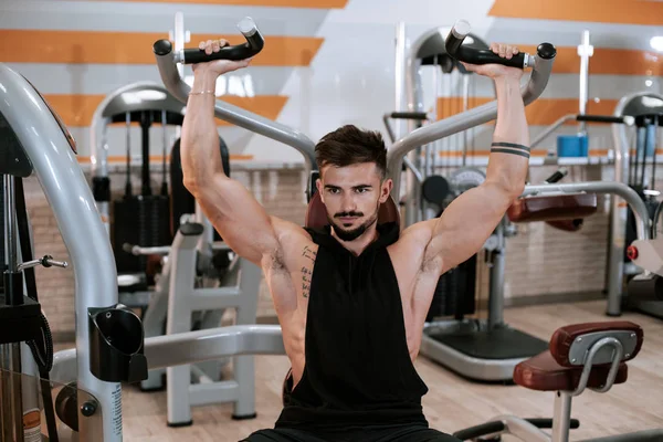 Forte atlético jovem fisiculturista modelo de fitness exercício tríceps com barra no banco no ginásio — Fotografia de Stock