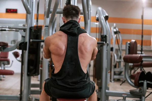 Em um moderno ginásio homem musculoso fazendo exercícios para seu tríceps concentrado trabalhando duro — Fotografia de Stock