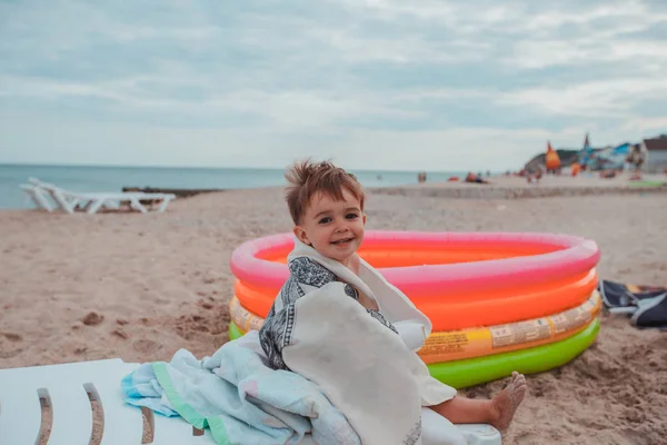 Niño feliz sentado en una tumbona en la playa —  Fotos de Stock