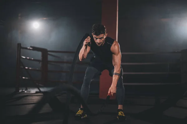 Atractivo chico musculatura entrenamiento en una clase de fitness cruz utilizando cuerdas concentradas haciendo su entrenamiento — Foto de Stock