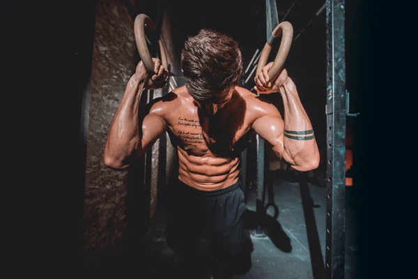 Devant la caméra beau gars dans un cours de fitness croix sombre, il termine son entraînement dur et intense — Photo