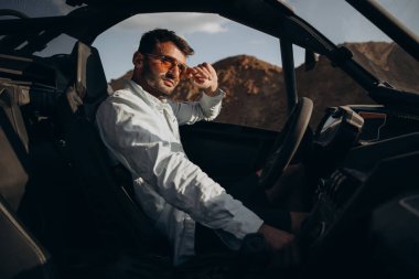 Yeni şık arabasında oturan çekici genç adamın portresi.