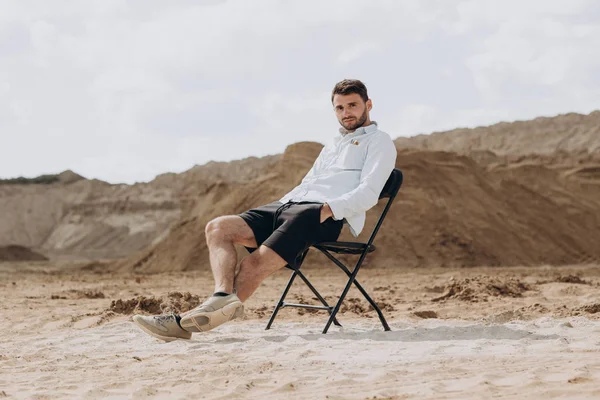 Knappe man een outdoor zitten op een stoel en poseren — Stockfoto