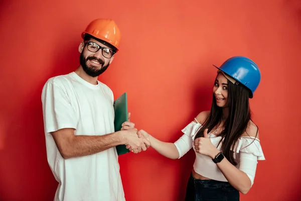 Due metà adulti costruttori lavoratori dando mano stretta isolato su sfondo rosso — Foto Stock