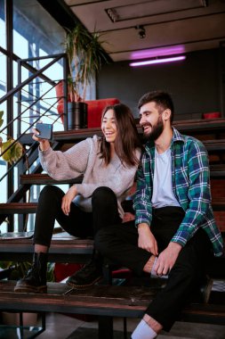 Büyük gülümseyen Japon bayan modern ofis stüdyosunun merdivenlerinde iş arkadaşıyla fotoğraf çekiniyor.