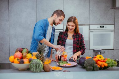 Sabahları modern bir mutfak karizmatik çifti kahvaltı için taze meyve suyu hazırlıyor.