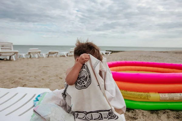 Lindo niño sentado en una silla de cubierta en la playa —  Fotos de Stock