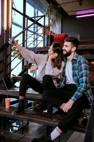 Büyük gülümseyen Japon bayan modern ofis stüdyosunun merdivenlerinde iş arkadaşıyla fotoğraf çekiniyor.