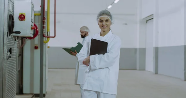 Primo piano ritratto di una donna matura attraente ingegnere guardando dritto della fotocamera e sorridente grande mentre tiene in mano un tablet elettronico in una grande fabbrica industriale — Foto Stock