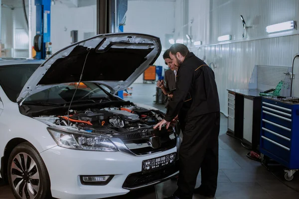 En un centro de servicio de coches mujer de buen aspecto en un traje de negocios que va al coche para comprobar el problema en un garaje de automóviles — Foto de Stock