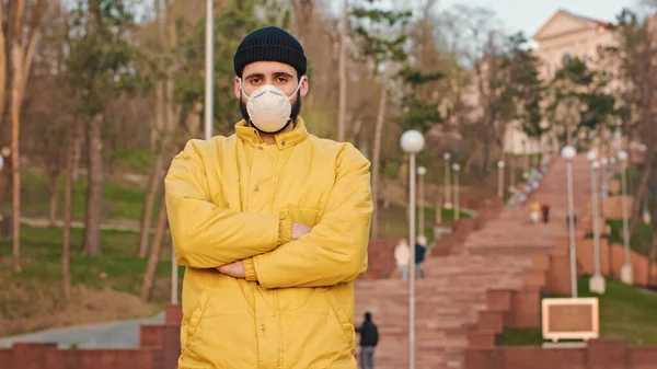 Junger Mann in gelber Jacke und Hut mit Schutzmaske, während er auf der Parktreppe steht. — Stockfoto