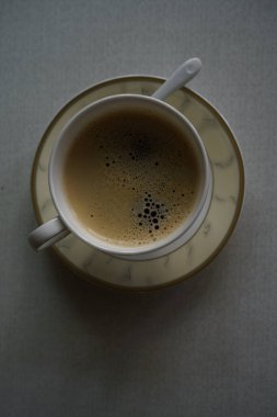 Hafif arka planda bir fincan kahve ve çay tabağı.