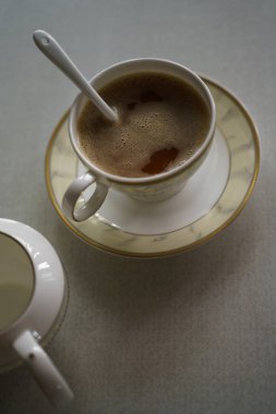 Bir fincan kahve, çay tabağı ve süt sürahisi.