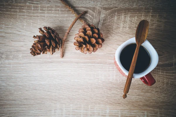 Чашка кофе и коричневая сосновая шишка на деревянном столе . — стоковое фото