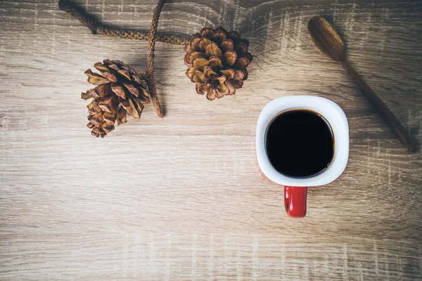 Чашка кофе и коричневая сосновая шишка на деревянном столе . — стоковое фото