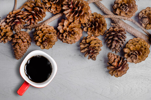 Top view cup of coffee and brown pine cones on wooden background