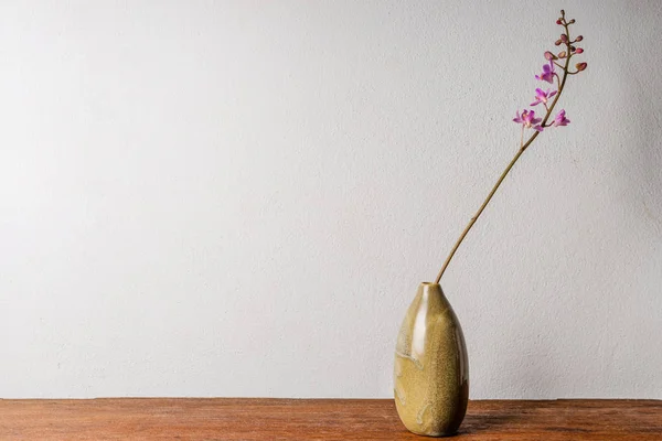 Różowy storczyk w wazonie na drewnianym stole — Zdjęcie stockowe