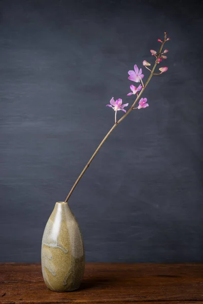 Różowy storczyk w wazonie na drewnianym stole — Zdjęcie stockowe