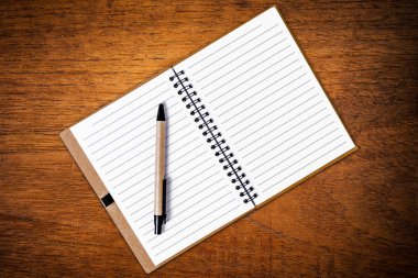 Açık defter kalem ahşap arka plan ile. Üstten Görünüm