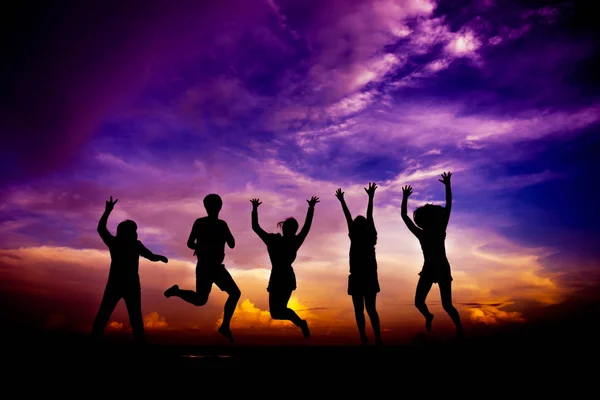Silhouette group of friends having fun jumps on sunset — Stock Photo, Image