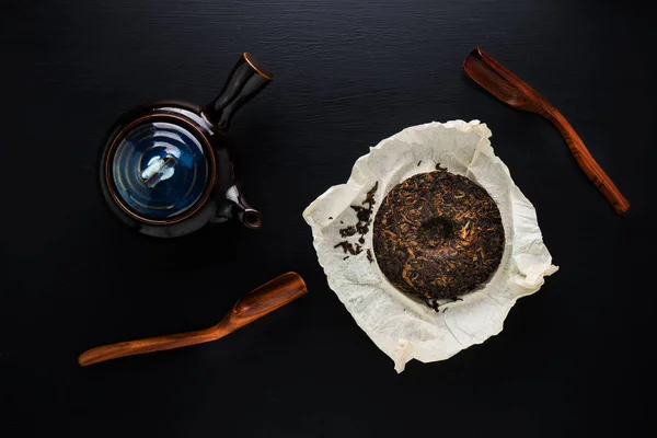 Panela de chá e chá seco verde na mesa preta — Fotografia de Stock