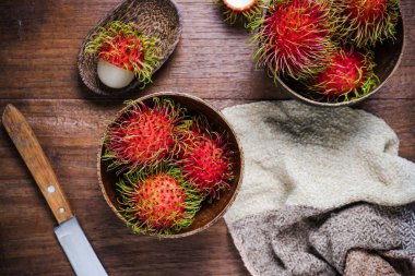Ahşap arka plan üzerinde bir woodean kase taze rambutans.