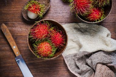 Ahşap arka plan üzerinde bir woodean kase taze rambutans.