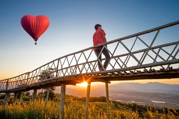 Silueta de hombre asiático de pie en el puente de bambú con rojo caliente —  Fotos de Stock