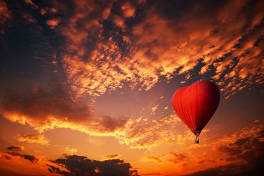 Kalp şeklinde kırmızı sıcak hava balonu, günbatımında uçan renkli sıcak hava balonu.