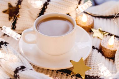 Düz yatıyordu. Süt, süveter, kaba örülmüş tekstil, siyah beyaz çizgili güvenli mumlar, altın yıldızlı beyaz arka plan. Homellik. Moda gençliği fotoğrafı