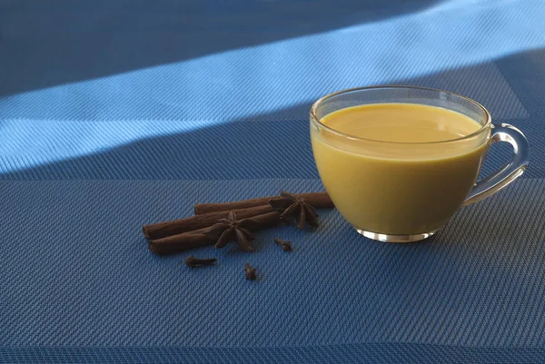 Golden milk, spices, cinnamon. Winter drink. Blue background.