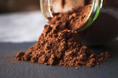 Siyah taş bir tahtanın üzerine kakao tozu serpiştirilmiş kavanoz. Boşluğu kopyala