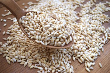 Pearl barley in a jar is scattered on a wooden table, close-up clipart
