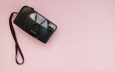 Pembe arka planda siyah film kamerası. Düz yatıyordu. Uzayı kopyala Üst görünüm