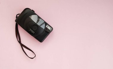 Pembe arka planda siyah film kamerası. Düz yatıyordu. Uzayı kopyala Üst görünüm