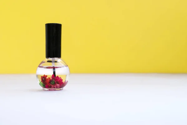 Nail care, cuticle oil in a beautiful bottle on a yellow background. Place for text