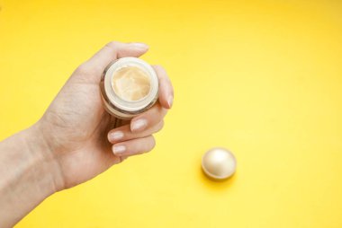 Sarı bir arka planda el kremi ile ilgilenmek. Metin için yer.